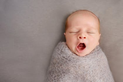 Swaddled baby yawning