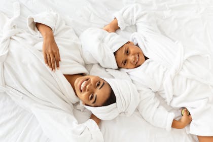 Mum and daughter lie on a bed in bath robes for spa day