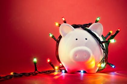 piggy bank wrapped in christmas lights on red background