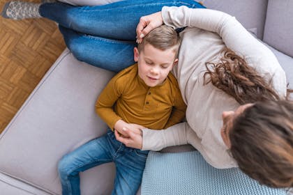 Boy lying on mum's lap on sofa