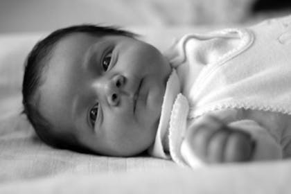 baby lying on bed in black and white