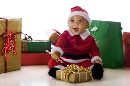Baby with Christmas present wearing Santa costume
