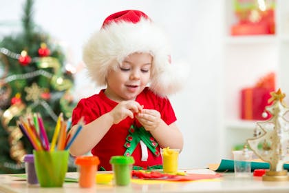 A child wearing a Santa hat making Christmas tree decorations