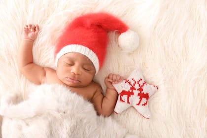 Sleeping newborn with Santa hat and soft toy star