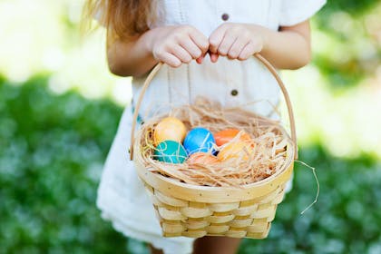 Girl holding a basket of colourful Easter eggs