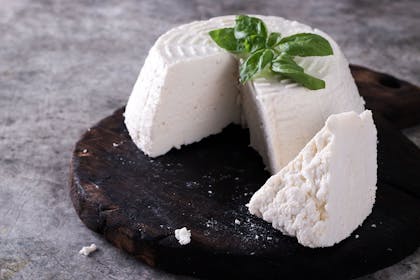 ricotta cheese topped with basil on a chopping board