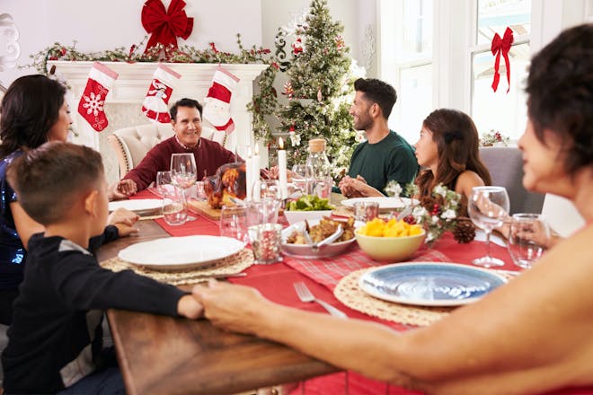 Family holding hands around the dinner table on Christmas day 
