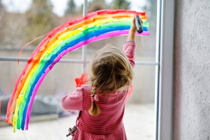 Kid painting rainbow on window