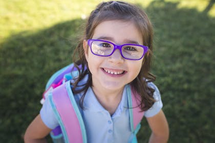 Little girl wearing school polo shirt and back pack