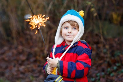 Kid holding sparkler while standing outside