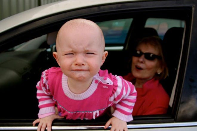 child crying and leaning out of car