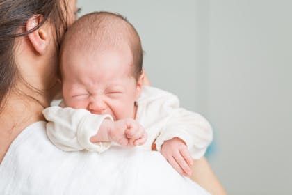 Baby with colic crying on mother's shoulder
