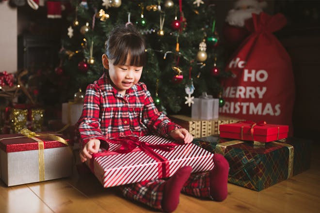 Little girl opening presents under the tree