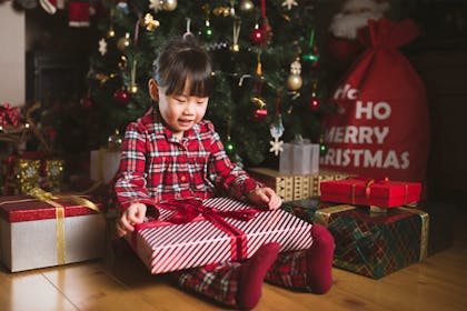 Little girl opening presents under the tree