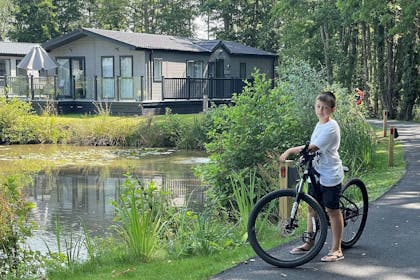 A boy and his bike stop by a lake at a Lovat Park holiday site.