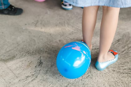 Balloon on floor next to kid's foot in party shoes 