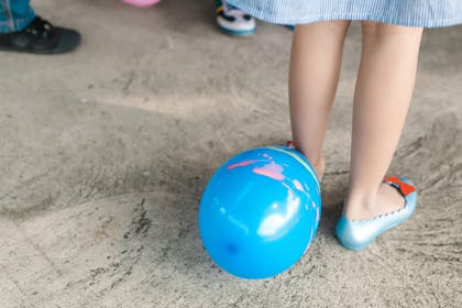 Balloon on floor next to kid's foot in party shoes