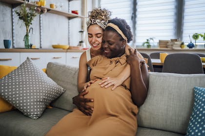 Woman cuddling pregnant woman
