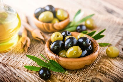Green and black olives in a wooden bowl