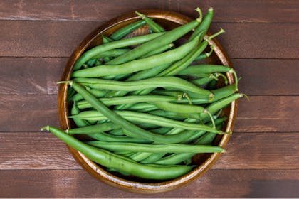 Basket of green beans on wooden table