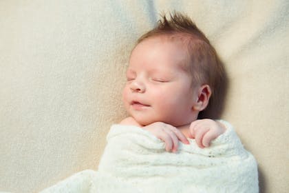 Baby swaddled in white knitted blanket 