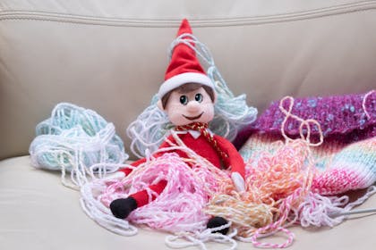 Christmas Elf on the Shelf sat in a pile of wool knitting