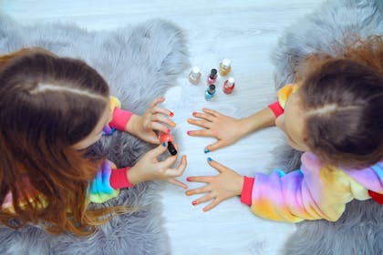 Two young girls painting each others nails