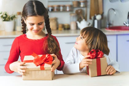 Brother and sister opening Christmas gifts together in the kitchen