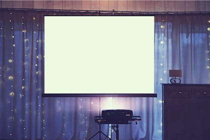 Powerpoint slideshow projector hung with purple curtain and fairy lights at party