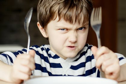 Angry little boy waiting for dinner