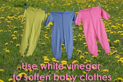 colourful baby clothes hanging from washing line in field of flowers
