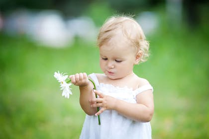 Toddler girl outside holding flower