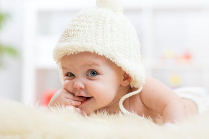 Cute baby wearing a hat chewing their fingers