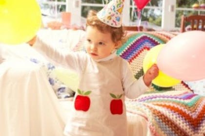 child in party hat at party with balloons