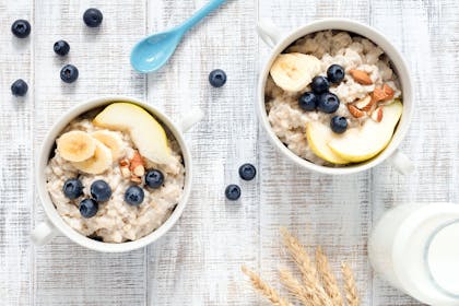 Two bowls of porridge with fruit and nuts