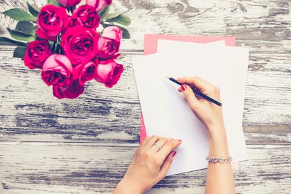 woman writing next to bunch of roses