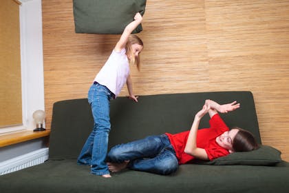 brother and sister fighting on sofa