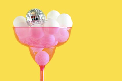 Pink champagne glass filled with ping pong balls and a mini disco ball