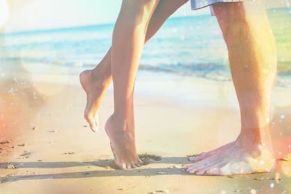 Couple's legs on beach by sea