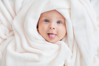 Cute baby surrounded by blankets sticking their tongue out