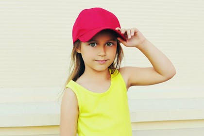 young girl smiling in red baseball cap from party goody bag