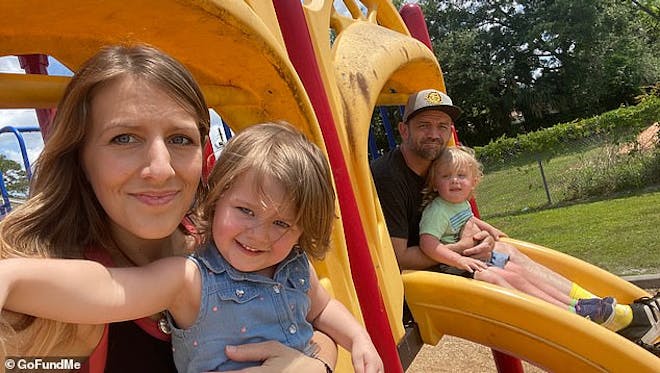 Mum and dad on a yellow slide holding their twins daughters