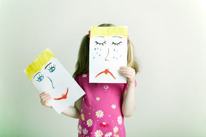Child with happy and sad face drawings