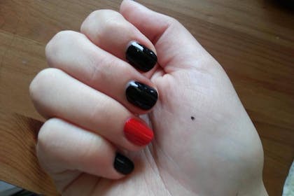 Hand with black nails and one red nail
