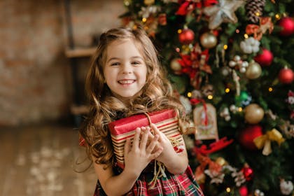 Little girl holding Christmas gift and smiling 