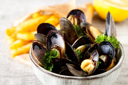Bowl of mussels next to chips