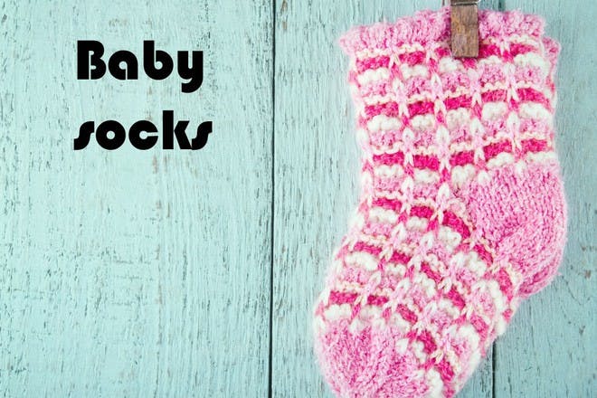 pink baby socks on blue wooden background
