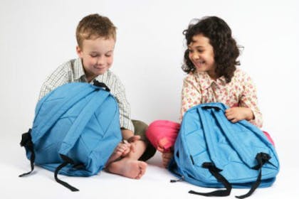 boy and girl sitting with school bags
