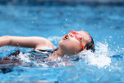 child swimming in a pool with goggles on