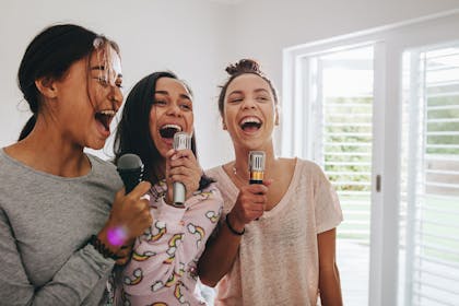 Teenage girls singing karaoke at sleepover